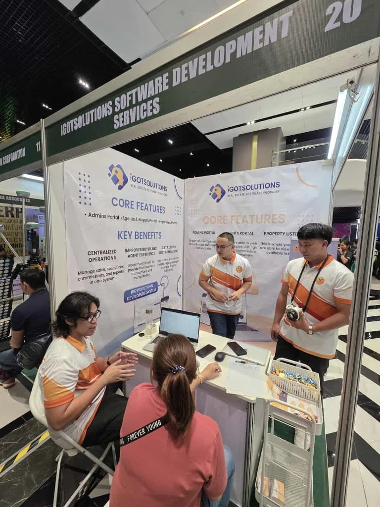 The iGotSolutions Software Development Services exhibit booth at CREBA 2025, showing Core Features and Key Benefits banners while staff demonstrate the software to a seated visitor.