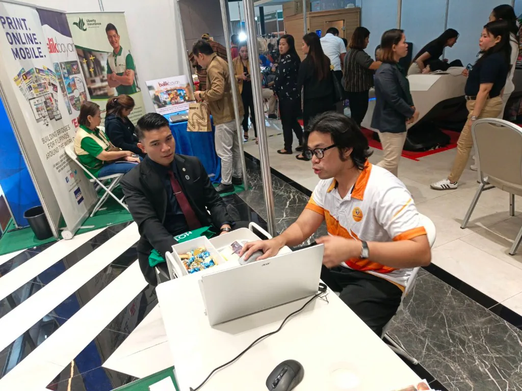 An iGotSolutions team member demonstrating the real estate software on a laptop to an attendee seated at the CREBA 2025 booth.